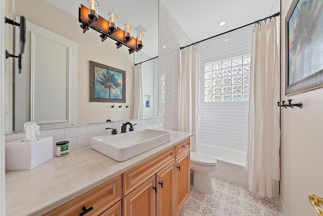 full bathroom featuring toilet, vanity, shower / bath combo with shower curtain, tile patterned flooring, and backsplash