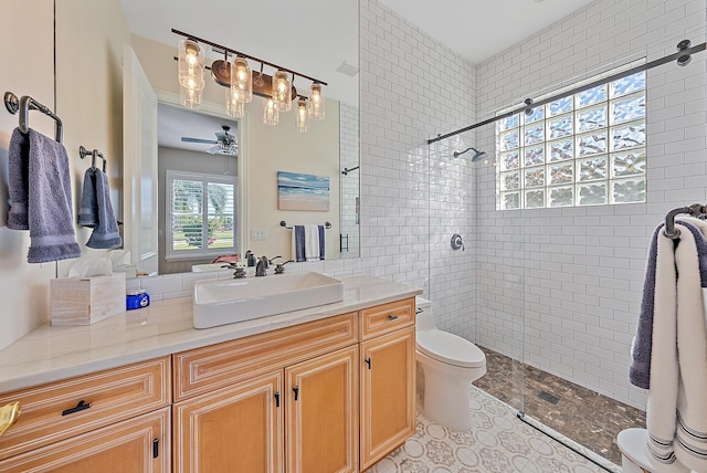 bathroom featuring tiled shower, toilet, vanity, ceiling fan, and tile patterned flooring