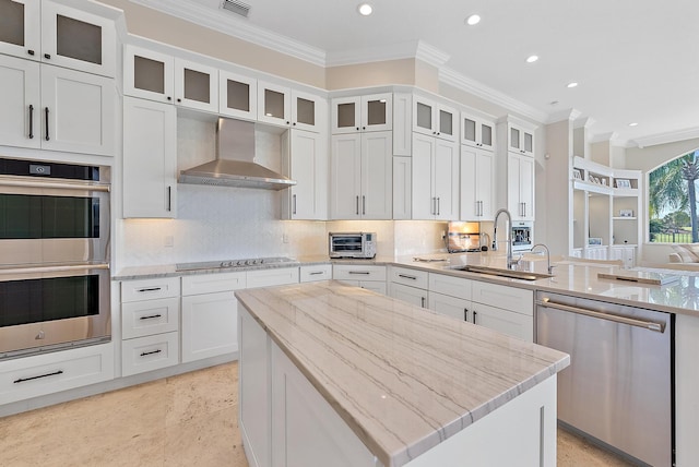 kitchen with wall chimney exhaust hood, sink, stainless steel appliances, light stone countertops, and white cabinets