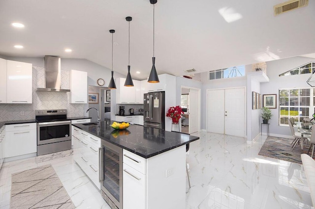 kitchen featuring wine cooler, wall chimney range hood, stainless steel appliances, a kitchen island with sink, and white cabinets