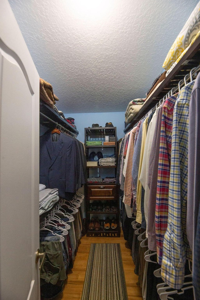 walk in closet with light hardwood / wood-style flooring