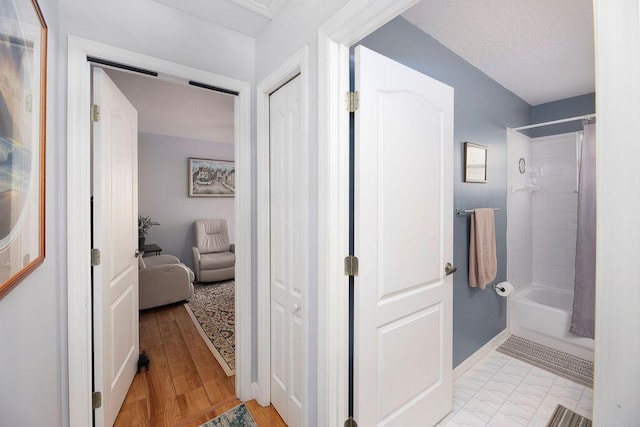 bathroom featuring shower / tub combo, hardwood / wood-style floors, and a textured ceiling