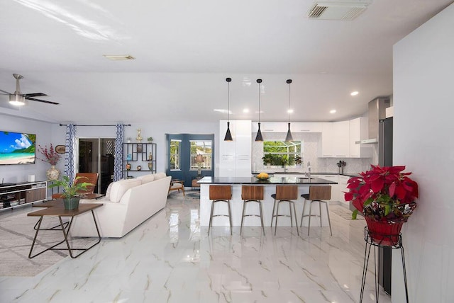 kitchen featuring a breakfast bar, decorative light fixtures, tasteful backsplash, white cabinets, and ceiling fan