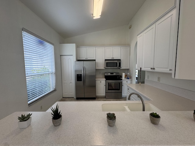 kitchen featuring sink, white cabinets, lofted ceiling, and appliances with stainless steel finishes