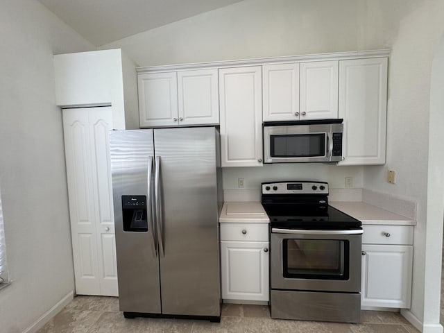 kitchen featuring vaulted ceiling, stainless steel appliances, and white cabinetry