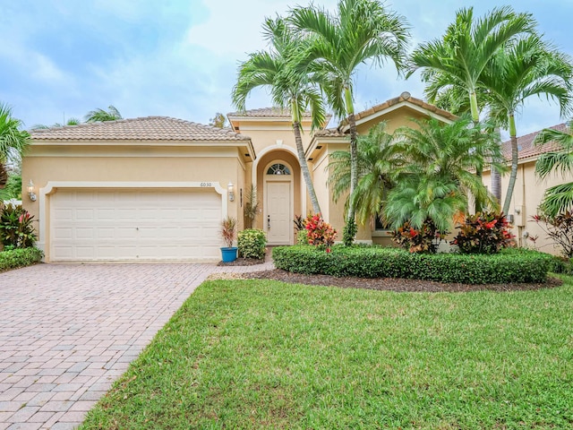 mediterranean / spanish-style home with a front yard and a garage