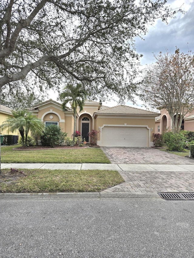 6001 Spring Lake Ter, Fort Pierce, FL 34951 - mediterranean / spanish home with stucco siding, a garage, decorative driveway, a front lawn, and central air condition unit