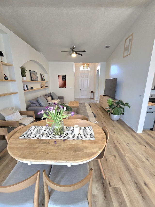 6001 Spring Lake Ter, Fort Pierce, FL 34951 - dining space featuring arched walkways, light wood-style floors, a ceiling fan, built in shelves, and lofted ceiling