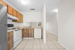 kitchen featuring white appliances, light tile patterned floors, and sink