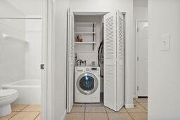 laundry area with washer / clothes dryer and light tile patterned floors