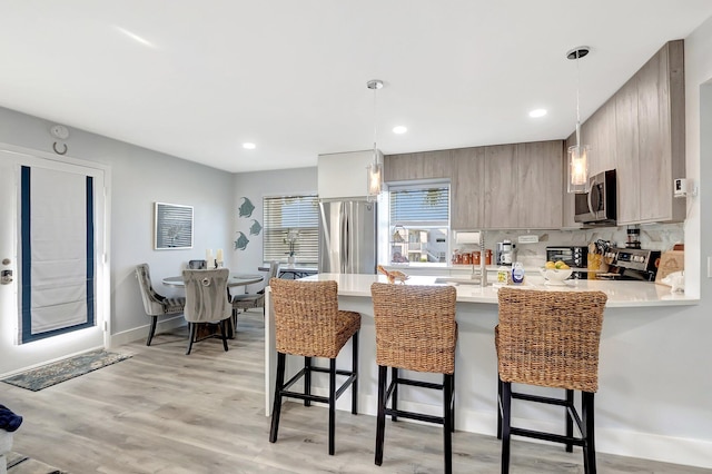 kitchen with kitchen peninsula, a breakfast bar, pendant lighting, and appliances with stainless steel finishes