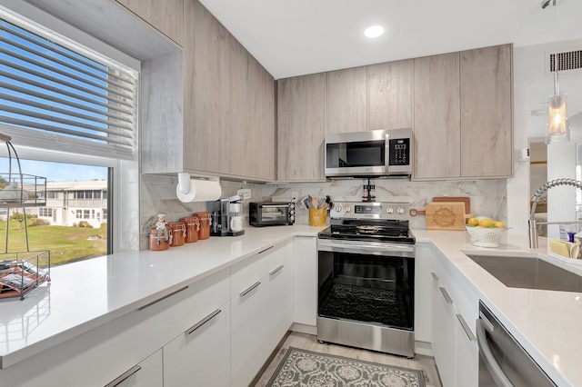 kitchen with backsplash, light brown cabinetry, sink, and appliances with stainless steel finishes