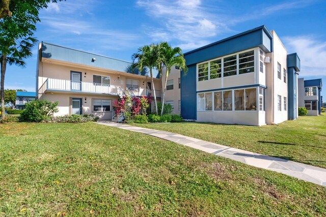 169 Flanders D, Delray Beach, FL 33484 - back of property with stucco siding and a yard