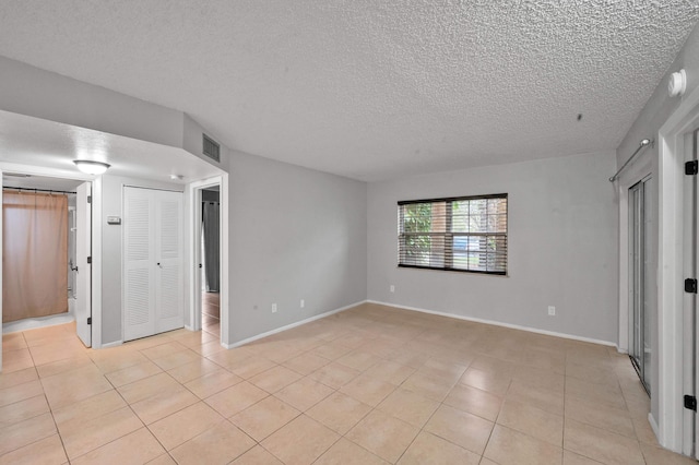 unfurnished bedroom with connected bathroom, a textured ceiling, and light tile patterned flooring