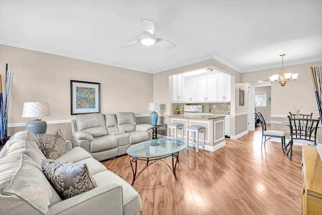 living room featuring light hardwood / wood-style flooring, ceiling fan with notable chandelier, and ornamental molding