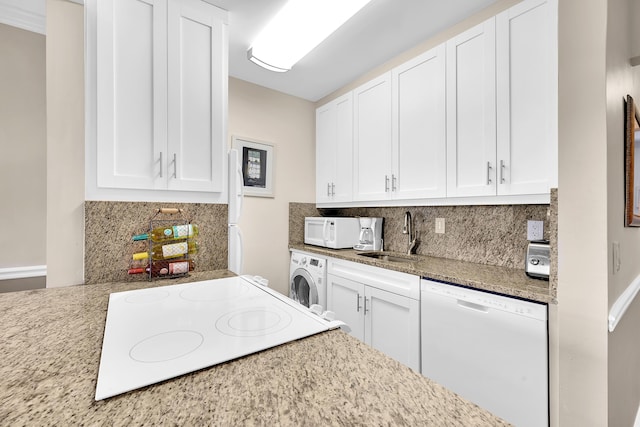 kitchen featuring white appliances, sink, light stone countertops, white cabinetry, and washer / clothes dryer