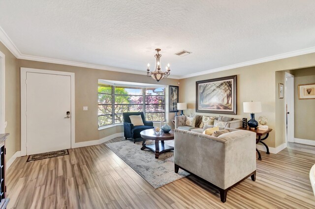 living room with a textured ceiling, light hardwood / wood-style flooring, crown molding, and an inviting chandelier