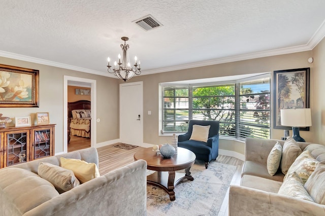 living room featuring a textured ceiling, a notable chandelier, crown molding, and light hardwood / wood-style flooring