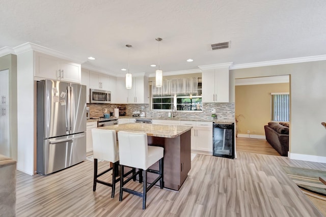 kitchen with pendant lighting, a center island, stainless steel appliances, and white cabinetry