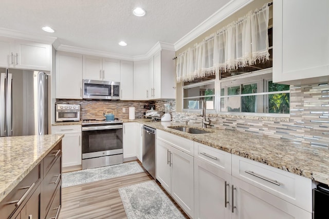 kitchen featuring white cabinets, backsplash, stainless steel appliances, and light stone counters