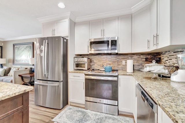 kitchen featuring backsplash, white cabinets, crown molding, light wood-type flooring, and stainless steel appliances