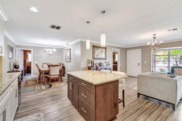 kitchen featuring pendant lighting, white cabinets, crown molding, light stone countertops, and light hardwood / wood-style floors