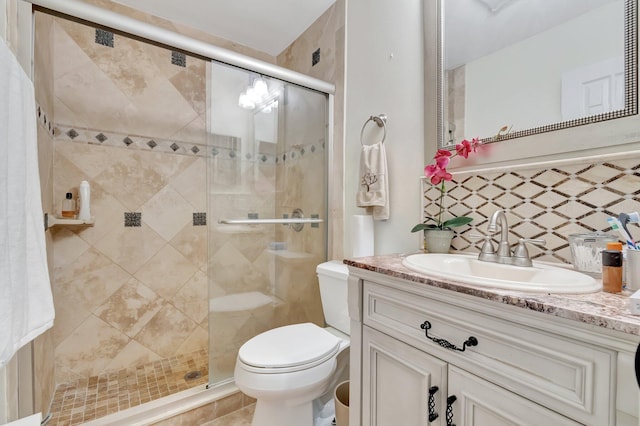 bathroom featuring backsplash, vanity, an enclosed shower, and toilet