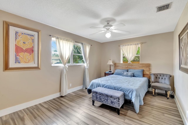 bedroom featuring a textured ceiling, light hardwood / wood-style floors, and ceiling fan