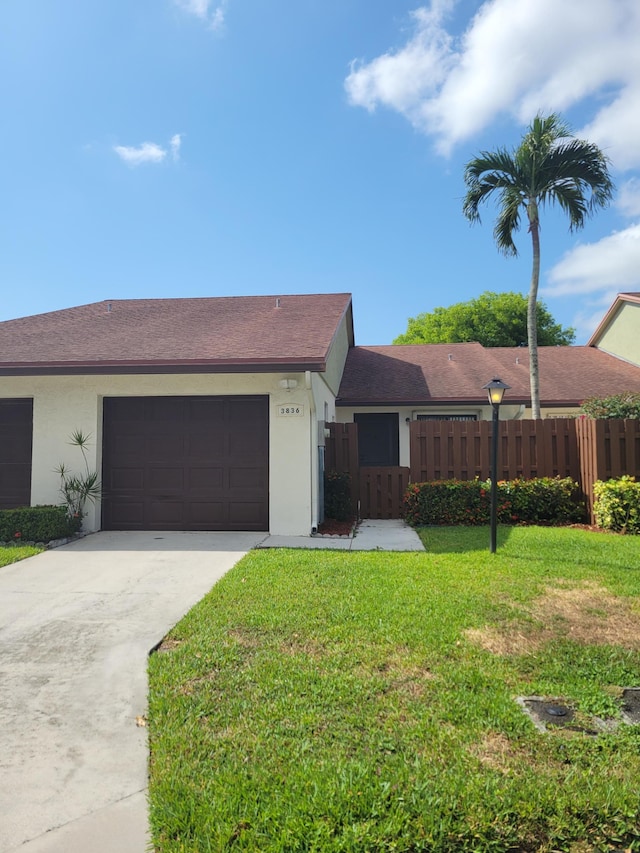 ranch-style home with a garage and a front lawn