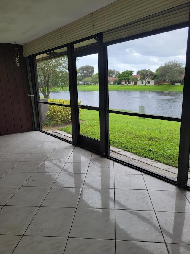 entryway with light tile patterned floors, a water view, and wood walls