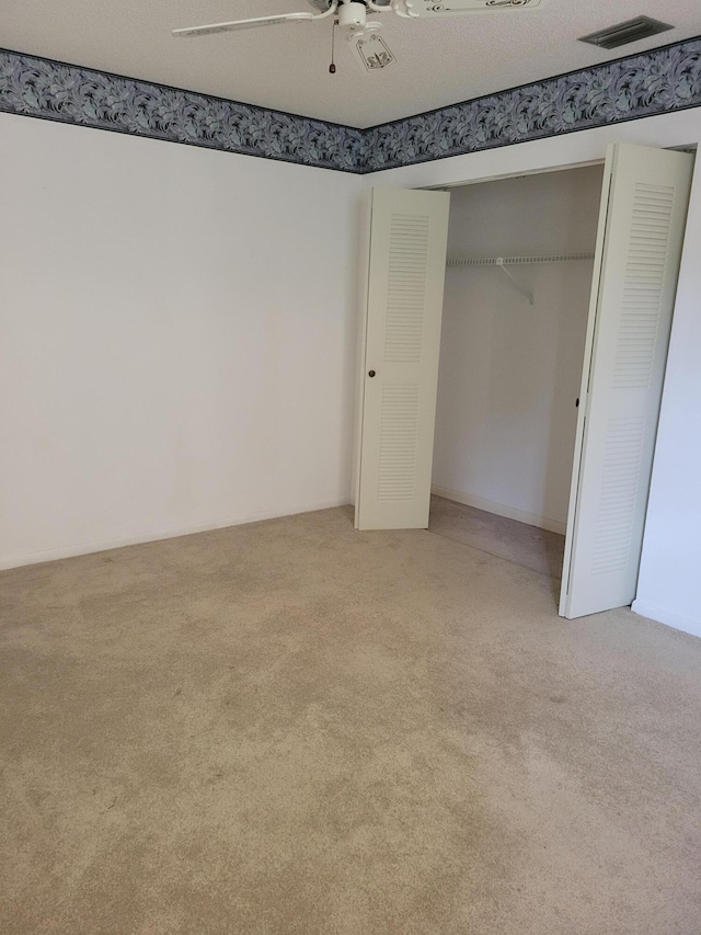 unfurnished bedroom featuring ceiling fan, a closet, carpet, and a textured ceiling