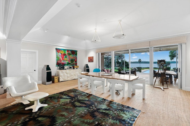 dining area featuring ornamental molding, a water view, hardwood / wood-style flooring, and a tray ceiling