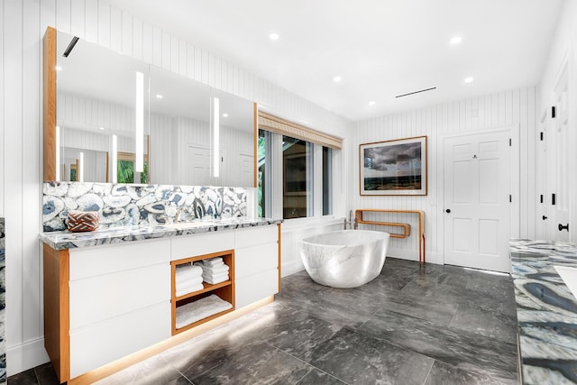 bathroom featuring vanity, a bathtub, and wooden walls