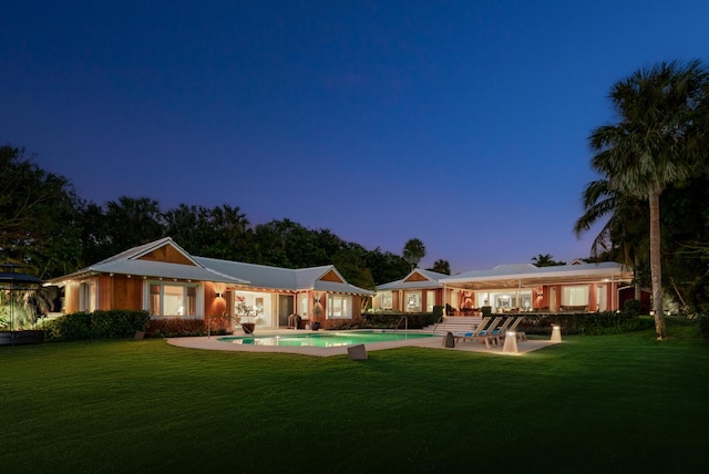 back house at dusk with a patio area and a yard