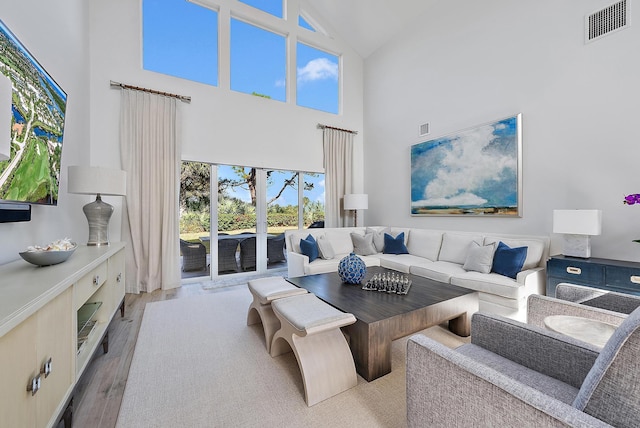 living room featuring light hardwood / wood-style flooring and a towering ceiling