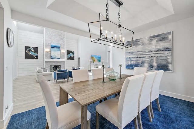 dining room with a raised ceiling and a large fireplace