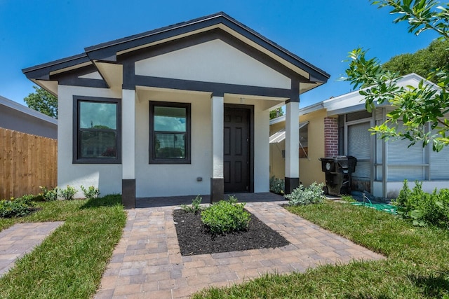 property entrance featuring stucco siding and fence