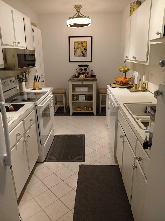 kitchen featuring light tile patterned floors, a sink, stainless steel appliances, light countertops, and white cabinets