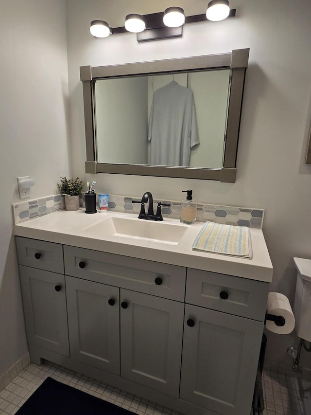 bathroom with baseboards, toilet, and vanity