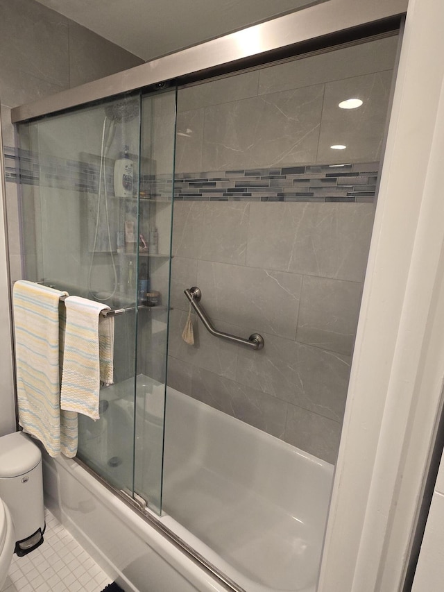 bathroom featuring tile patterned flooring, toilet, and combined bath / shower with glass door