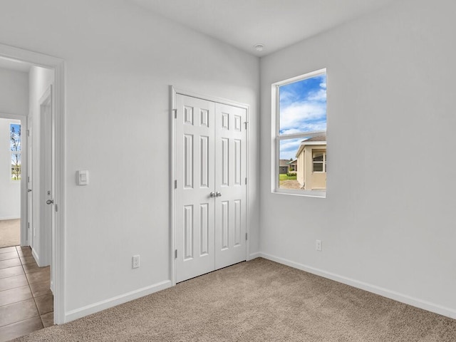 unfurnished bedroom with light colored carpet and a closet