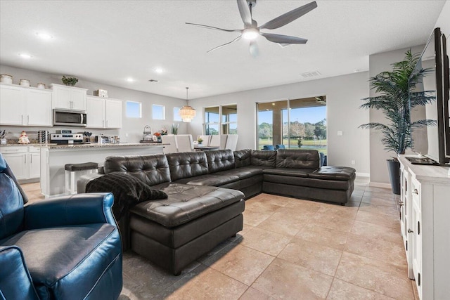 living room with light tile patterned floors, a textured ceiling, and ceiling fan