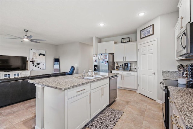 kitchen with sink, light stone counters, a center island with sink, appliances with stainless steel finishes, and white cabinets