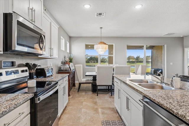 kitchen featuring sink, white cabinetry, decorative light fixtures, appliances with stainless steel finishes, and a notable chandelier