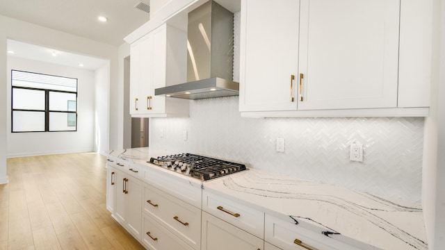 kitchen with white cabinets, light stone countertops, wall chimney exhaust hood, and stainless steel gas cooktop