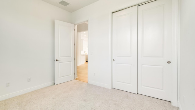 unfurnished bedroom featuring light carpet and a closet