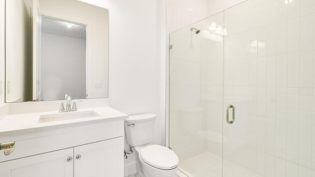 bathroom featuring a shower with door, vanity, and toilet