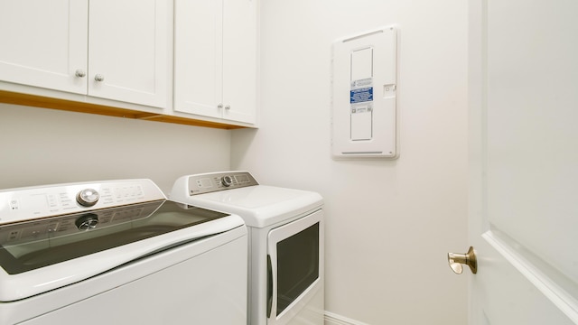 clothes washing area with cabinets and separate washer and dryer