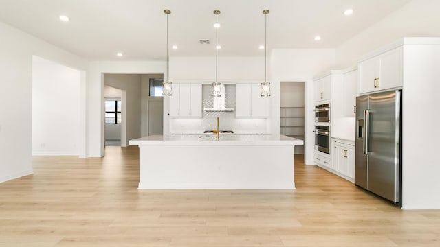 kitchen featuring white cabinets, decorative light fixtures, stainless steel appliances, and an island with sink