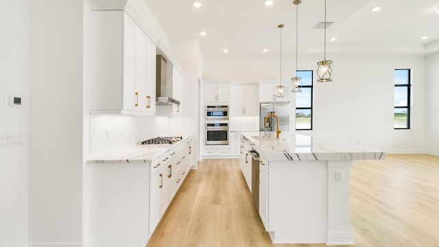 kitchen featuring tasteful backsplash, wall chimney exhaust hood, decorative light fixtures, white cabinetry, and a large island